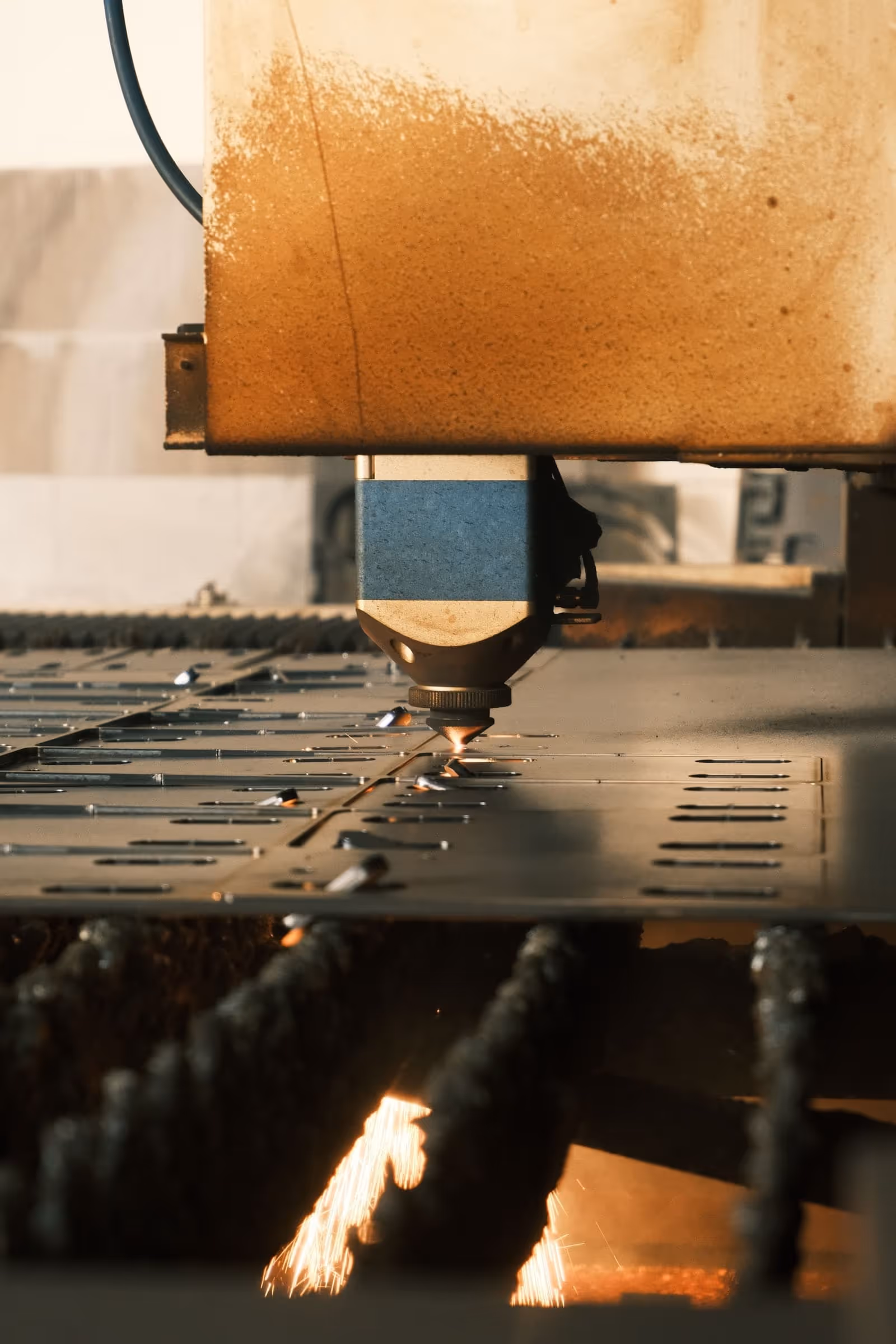 CNC laser cutting head at work on a steel sheet, sparks flying